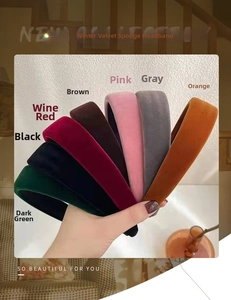 Close-up of diverse velvet sponge headbands in multiple colors held by a hand