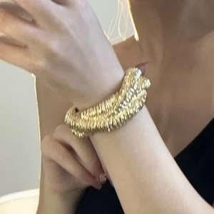 Macro shot of gold wide layered lava spiral cuff bracelet on female wrist