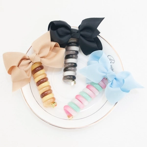 Three colorful spiral phone cord hair ties with large fabric bows on ceramic plate