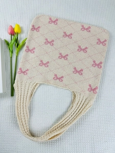 Close-up of beige knitted tote bag with pink bow patterns and a soft knit texture