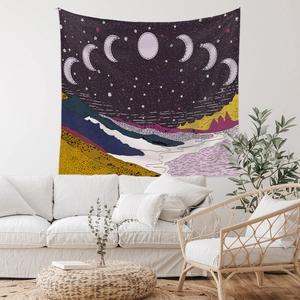 Detail of starry night mountain tapestry with moon phases over a white sofa