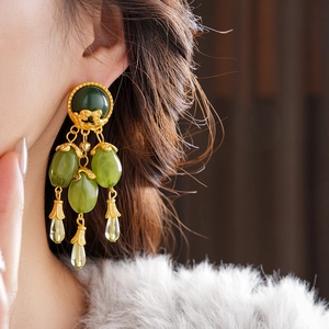 Detailed view of vintage gold tassel earrings with olive green oval and teardrop stones
