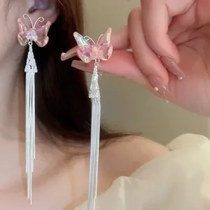Detailed view of silver butterfly tassel earrings with pink gradient wings on a model