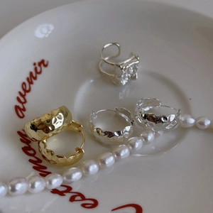Detailed shot of hammered silver and gold earrings with a stylish irregular ring