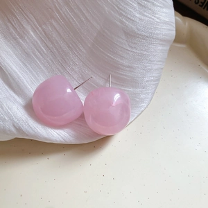 Close-up of pink resin flower earrings on soft silk fabric with elegant metal studs