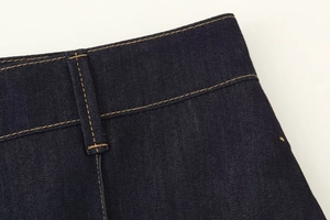 Détail de la taille en denim bleu foncé avec double couture jaune et passants de ceinture