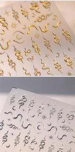 Detailed view of gold and silver snake skin nail art stickers with moon and star patterns