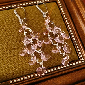 Close-up of pink crystal heart tassel earrings on vintage moss green velvet background