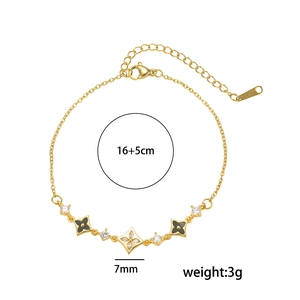 Gold clover bracelet with black enamel and zircon accents on a white background