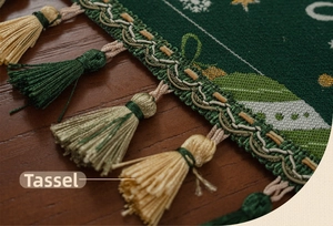 Detailed close-up of dark green Christmas table runner with tassels and snowflake patterns