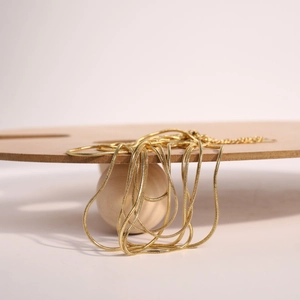 Macro detail of 1.5mm golden snake chain featuring lobster clasp and adjustable tail