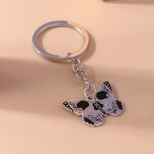 Detailed view of silver butterfly keychain with gothic skull pattern and polished chain