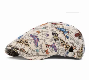 Detail der khakifarbenen Schiebermütze mit bunten Schmetterlings-Stickereien und Schnalle