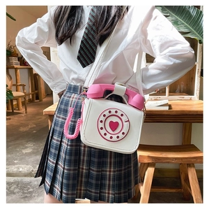 Close-up detail of a novelty telephone-shaped crossbody bag worn with a preppy outfit