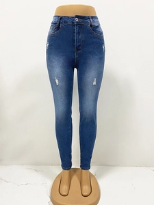 Detail van de blauwe skinny jeans met hoge taille, versleten gaten en gewassen denimtextuur