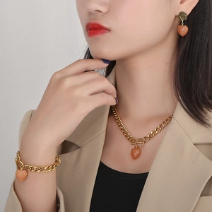 Detailed view of women gold OT clasp jewelry set with heart stones worn by model