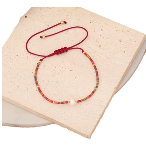 Handmade Bohemian beaded bracelet with red cord, gold accents and a center pearl
