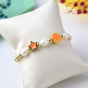 Detail of beaded bracelet with freshwater pearls, orange stars and happy face charms