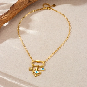 Gold multi-pendant necklace with evil eye and star moon charms on a textured background