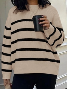 Detail of a woman holding a coffee cup wearing a striped beige and black knit sweater