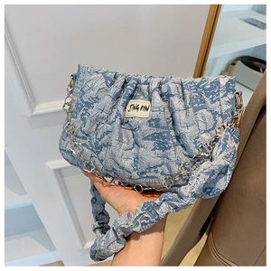 Detail of blue pleated cloud bag featuring jacquard fabric and silver floral metal chain