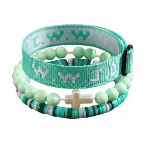 Detailed macro view of mint green WWJD woven strap and multi-beaded bracelet set