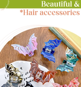 Detailed view of bat-shaped acrylic hair claws with marble and tortoiseshell textures