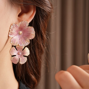 Close-up of pink gradient enamel flower earrings with gold edges on a model's ear