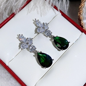 Close-up of emerald pear-shaped drop earrings with marquise zircon floral clusters