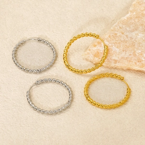 Minimalist twisted rope hoop earrings in gold and silver finish on textured background