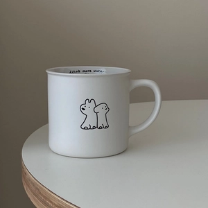 Close-up of white ceramic mug with cartoon puppy and 'drink more water' inner text