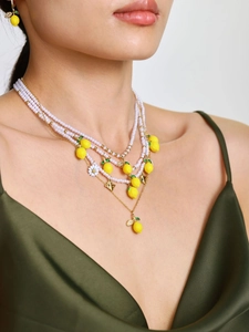 Collana di perle multistrato con ciondoli limone e margherita su abito in seta verde