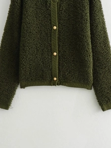 Detailopname van het donkergroene bouclé vest met getextureerde gouden metalen knopen