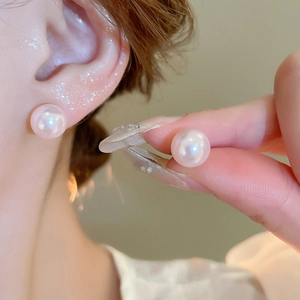 Close-up of minimalist elegant faux pearl stud earrings with high luster pinkish sheen