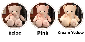 Detail of plush teddy bears in beige, pink and yellow with bow and rabbit embroidery