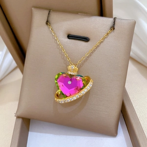 Macro detail of crown and colorful heart crystal pendant on a gold necklace