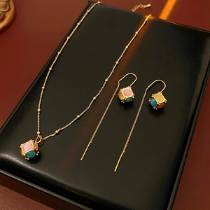 Macro shot of gold-plated necklace and earrings set with pink and blue cat-eye stone cubes