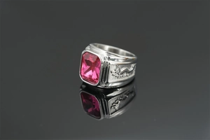 Macro detail of silver dragon relief carving and purple gemstone on men's steel ring