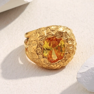 Macro detail of gold flower ring with yellow gemstone on a textured stone surface