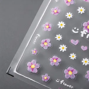 Detail of floral nail stickers featuring purple flowers and daisies on adhesive film