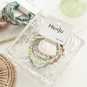 Macro shot of colorful braided hair ties set in a glass bowl with macaron color tones