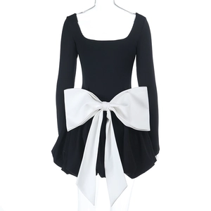 Détail d'une robe moulante noire avec un grand nœud décoratif blanc contrasté à la taille