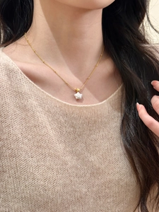 Gros plan du collier étoile plaqué or avec perle porté par un mannequin féminin