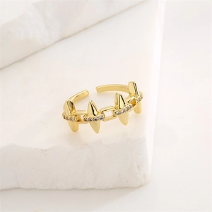 Détail de la bague dorée à pointes ornée de zircons sur un support en marbre