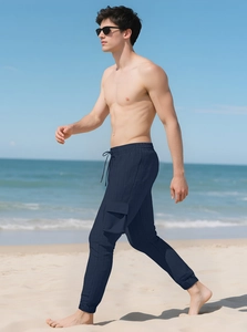 Men's navy cargo joggers with textured fabric and drawstring waist in a beach setting