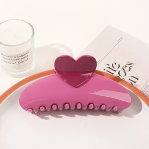 Pink and purple heart claw clip on a white plate with aesthetic lifestyle props