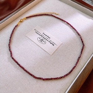 Detailed macro view of dark red square beads necklace with golden lobster clasp and chain