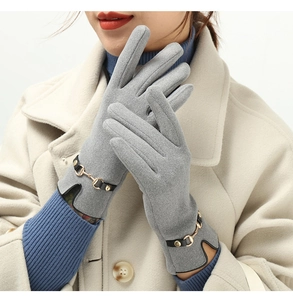 Close-up of gray thermal gloves with a gold horsebit buckle and faux suede texture