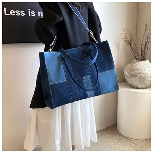 Detail of blue patchwork denim tote bag with adjustable shoulder strap and sturdy handles