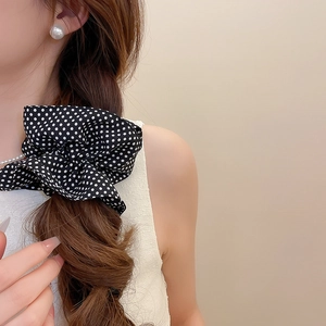 Close-up of black polka dot fabric scrunchie on side braid with elegant pearl earring